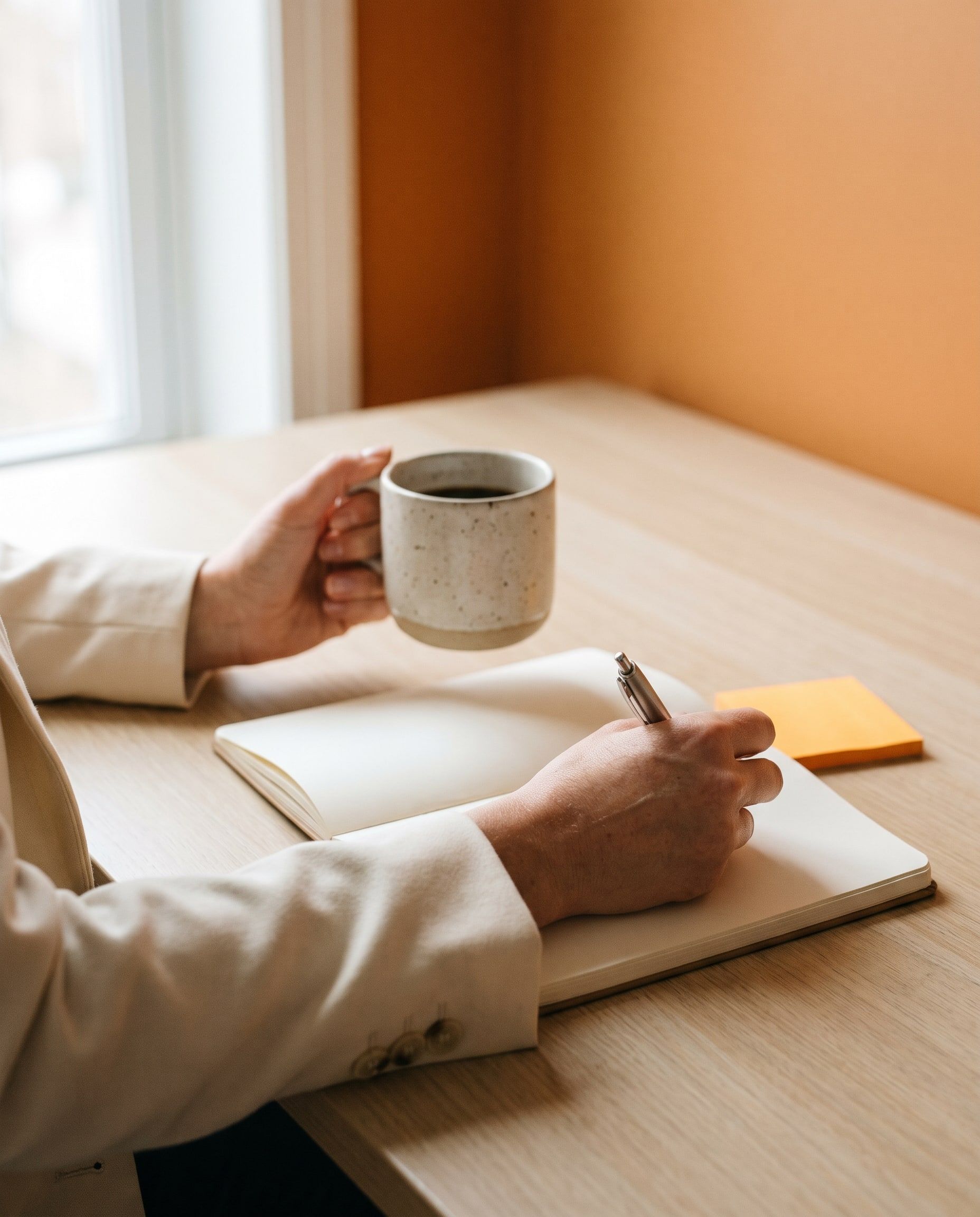 Manos con una taza de café y una libreta abierta
